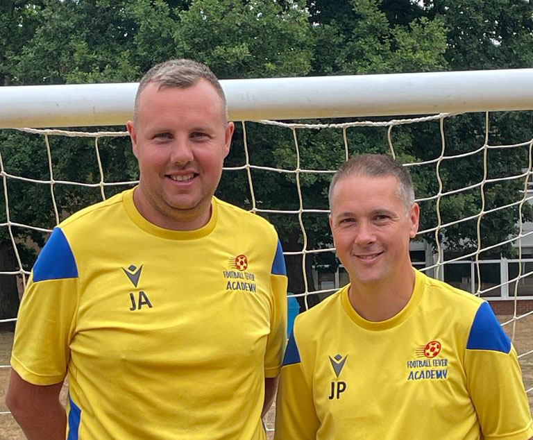 coaches John and Joe stood in front of a goal in their FFA football shirts